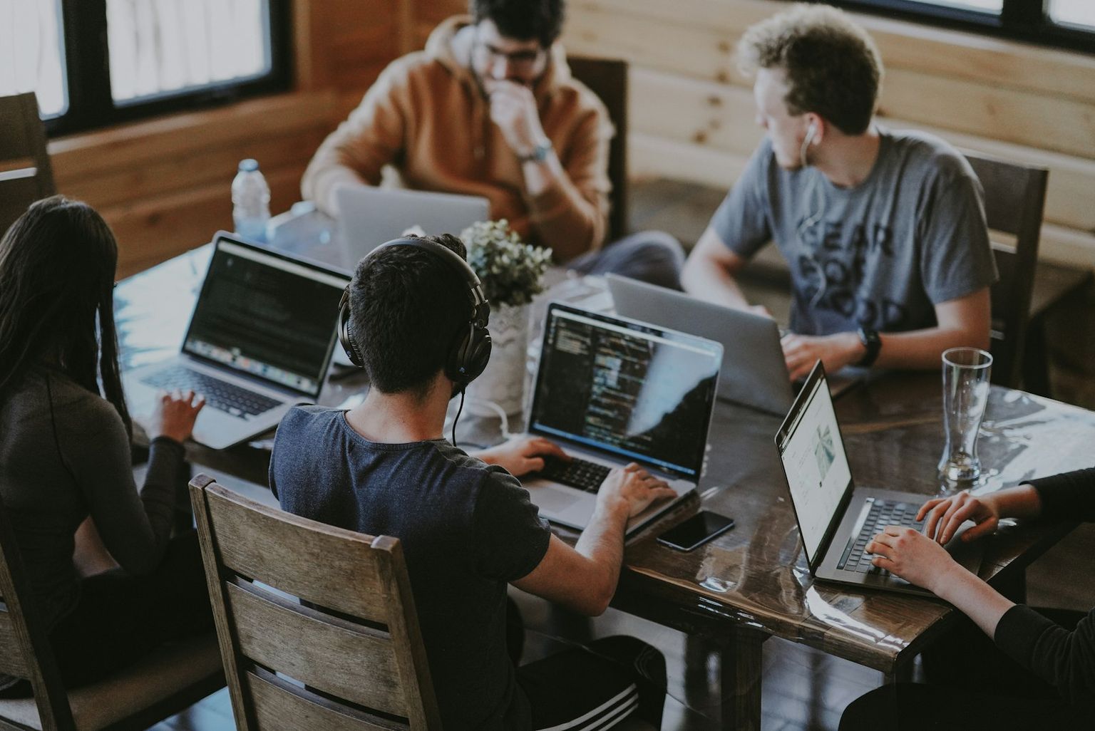 Mehrere Menschen arbeiten an Laptops an einem Holztisch