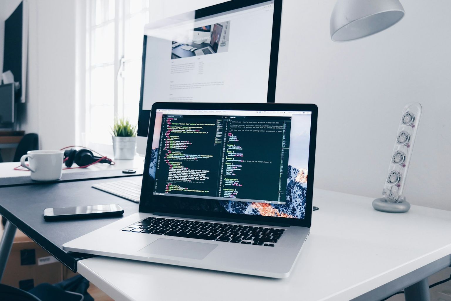 Laptop mit Programmcode auf einem Schreibtisch